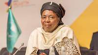 Nkosazana Dlamini-Zuma sitzt an einem Tisch und schaut lächelnd an der Kamera vorbei.