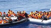 Soldaten mit Speedboot retten Menschen aus Schlauchboot.