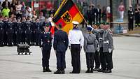 Soldaten stehen an der Truppenfahne auf einem Platz