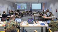 Soldaten und Zivilisten verfolgen einen Vortrag im Seminarraum bei der Cyber Defence NATO Übung Locked Shields 2016