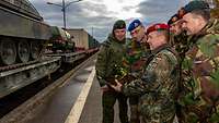 Soldaten unterschiedlicher Nationen besprechen den Umschlag von Fahrzeugen am LogHub in Pfungstadt.