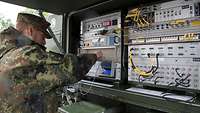 Soldat bedient eine mobile Satcom-Anlage