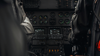 Die Mittelkonsole eines Hubschraubers ist zu erkennen, flankiert von dem Piloten und Copiloten.