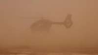 Ein Hubschrauber wirbelt viel Sand in der Wüste auf