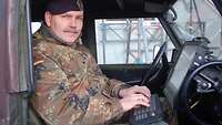 Soldat sitzt im Auto an seinem Laptop