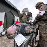 Zwei Soldaten versorgen einen Übungspatienten vor einem Sanitätszelt