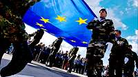 Soldaten verschiedener Nationen halten EU-Flagge