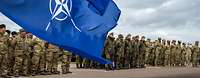 Angetretene Soldaten, im Vordergrund NATO-Flagge