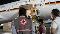 Zwei Männer vom Indian Red Cross Society (IRCS) und ein deutscher Soldat beobachten das Entladen des Airbus A350