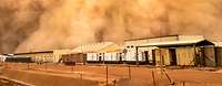 Eine Sandwolke rollt über ein Camp aus flachen Häusern und Containern