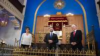 Ministerin Kramp-Karrenbauer steht mit zwei Männern in einer Synagoge vor einem Altar