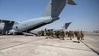 Mehrere Soldaten mit Ausrüstung laufen zu einem Transportflugzeug vom Typ A400M am Flughafen in Taschkent