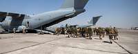 Mehrere Soldaten mit Ausrüstung laufen zu einem Transportflugzeug vom Typ A400M am Flughafen in Taschkent