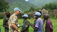 Eine deutsche Soldatin im Gespräch mit afrikanischen Sicherheitsvertretern, im Hintergrund ein Gebirge