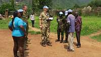 Eine deutsche Soldatin mit Notizbuch steht zwischen afrikanischen UN-Sicherheitsvertretern