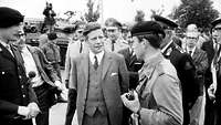 Schwarz-Weiß-Aufnahme: Umgeben von Pressevertretern und Soldaten spricht Helmut Schmidt mit einem Soldaten.