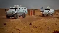 Zwei Fahrzeuge der UN fahren durch die Wüste