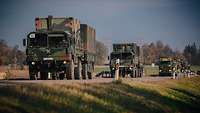 Mehrere Lkw der Bundeswehr fahren hintereinander über eine Landstraße