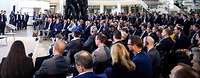 Viele Personen sitzen in einem Foyer und hören einer Podiumsdiskussion zu.