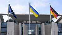 Die Flaggen von Europa, der Ukraine und Deutschland wehen an Masten vor dem Bundeskanzleramt.