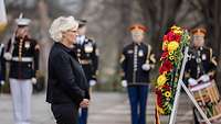 Minister Lambrecht stands in front of a wreath of flowers