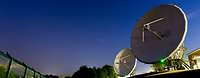 Zwei Radaranlagen mit riesigen Satellitenschüssel von unten fotografiert vor einem Sternenhimmel.