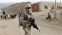Ein Soldat patrouilliert durch ein afghanisches Dorf.