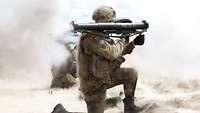 Auf einem Knie stehend feuert ein Soldat eine Panzerfaust ab