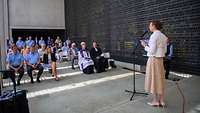 Ein Frau spricht am Mikrofon im Ehrenmal der Bundeswehr beim multireligiösen Gottesdienst zu den Teilnehmern