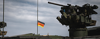 A weapon station with a heavy machine gun, the German flag flies in the background.