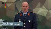 General Gerhartz steht vor einer Wand mit dem Polygonemuster der Bundeswehr