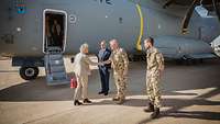 Christine Lambrecht steht vor der Treppe ihres Dienstflugzeuges und wird von deutschen Soldaten begrüßt.