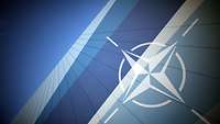 Vor blauem Hintergrund ist das Emblem der NATO zu erkennen.