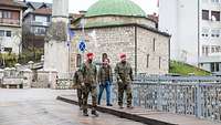 Mehrere Soldaten und ein Zivilist laufen über eine Brücke