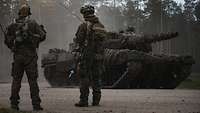 Zwei Soldaten stehen vor einem Panzer vom Typ Leopard