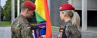 Zwei Soldaten bereiten das Hissen der Regenbogenflagge vor.