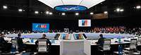 Die Teilnehmenden einer NATO-Sitzung sitzen in einem Konferenzsaal an einem großen runden Tisch 