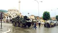 Ein Transportpanzer Fuchs und ein Achtsitzer stehen in Prizrens Innenstadt an Moschee am Marktplatz
