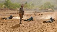 Ein deutscher Soldat steht hinter mehreren malischen Soldaten, die Schießübungen absolvieren