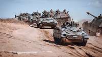 Mehrere Panzer vom Typ Marder und Panzerhaubitzen 2000 fahren über sandiges Gelände