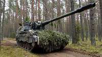 Eine Panzerhaubitze 2000 steht aufmunitioniert und abmarschbereit in einem Waldgebiet