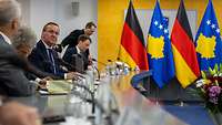 Pistorius sitzt mit anderen Mitgliedern seiner Delegation an einem Tisch, Flaggen von Deutschland und Kosovo im Hintergrund.