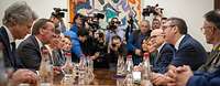 Boris Pistorius und Aleksandar Vucic sitzen sich beim Gespräch am Tisch gegenüber, drum herum stehen weitere Fotografen.