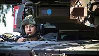 Eine Soldatin schaut aus einer Luke im Brückenlegepanzer Typ Leguan.