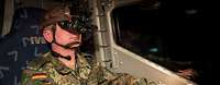 Ein Soldat sitz mit einer Bildverstärkerbrille querschnittlich in einem Kraftfahrzeug und fährt.