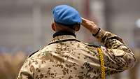 Von hinten ist ein deutscher Soldat mit einem UN-Barett in blau zu erkennen, er grüßt militärisch.
