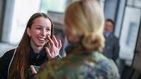 Eine Soldatin trägt mit ihrem Finger Tarnschminke auf die linke Wange einer jungen Frau auf 