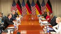 Der deutsche und amerikanische Verteidigungsminister sitzen mit mehreren Personen an einem Tisch 