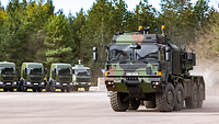 Ein LKW der Firma Rheinmetall steht neben einer Reihe anderer Lastkraftfahrzeuge, die unscharf zu erkennen sind.