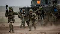 Soldaten in voller Montur stürmen aus einem Gefechtsfahrzeug auf einem Truppenübungsplatz